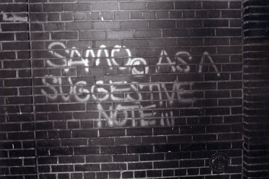 Black and white photograph of the the words SAMO© AS A SUGGESTIVE NOTE scrawled on a brick wall.