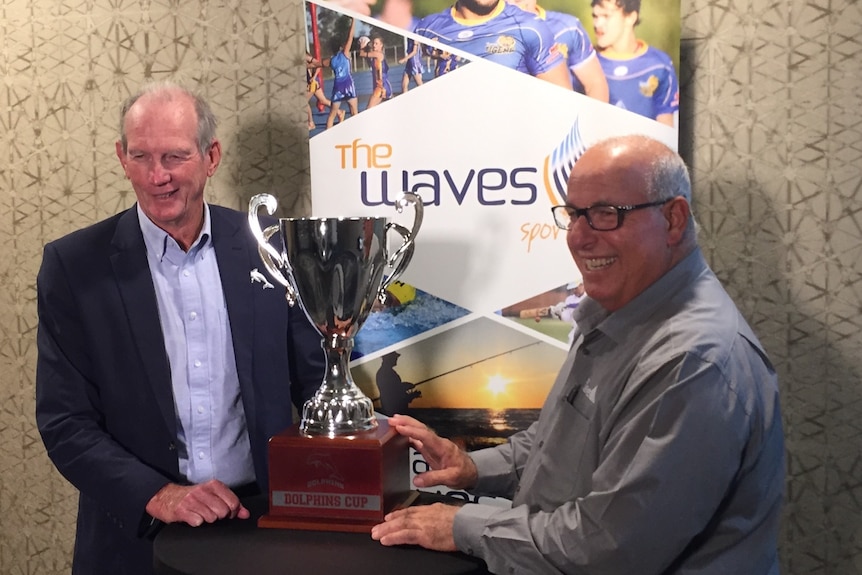 Deux hommes plus âgés posent pour une photo avec le nouveau trophée de la coupe des dauphins