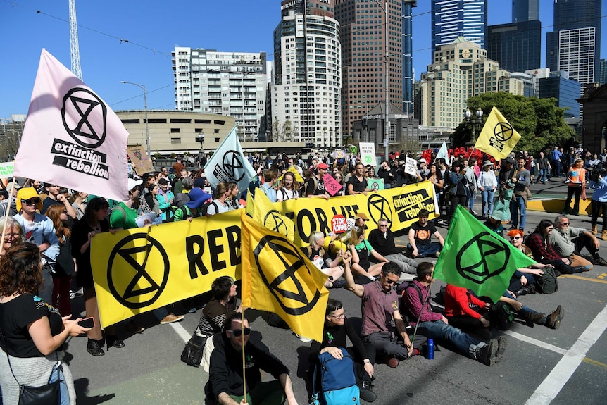 Protesters hold colourful banners and signs as they block a city road.