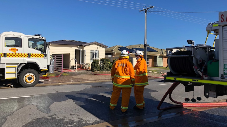 CFS firefighters outside a damaged home.