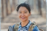 A woman with  black hair wears a military uniform and smiles at the camera