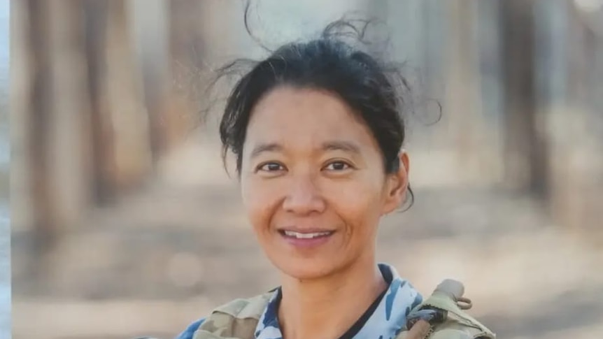 A woman with  black hair wears a military uniform and smiles at the camera