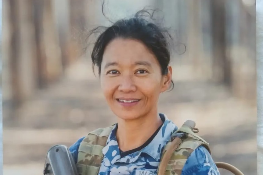 A woman with  black hair wears a military uniform and smiles at the camera