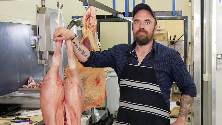Butcher Russell Critch standing next to pig carcass