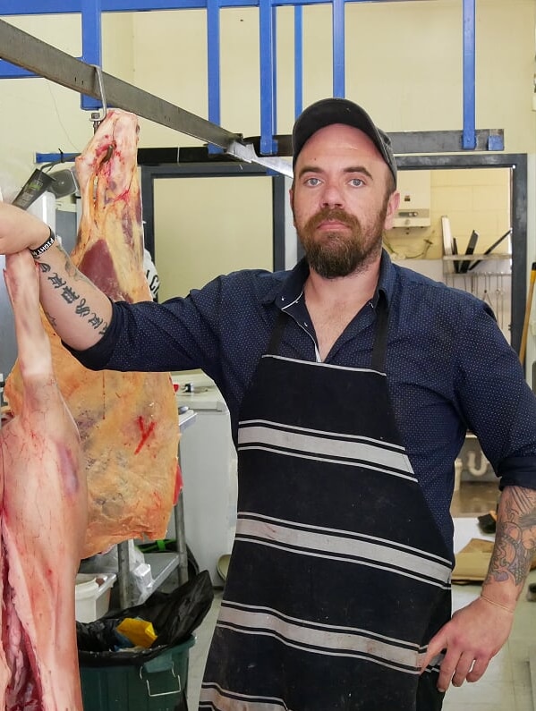 Butcher Russell Critch standing next to pig carcass