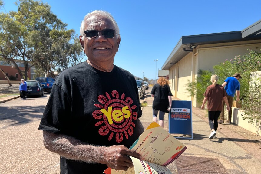 an aboriginal man wearing a 'yes' t-shirt smiling at the camera. 