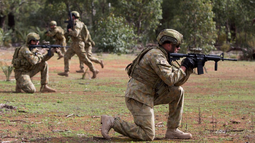 An army squad hold guns during a training exercise.