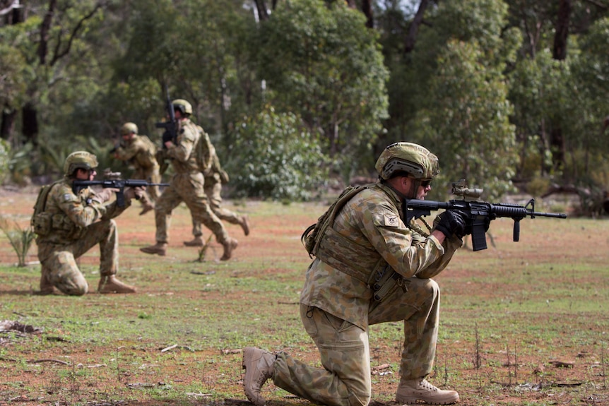 An army squad hold guns during a training exercise
