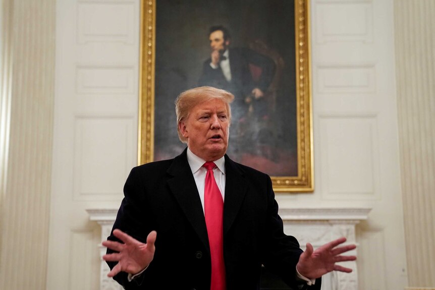 Donald Trump gesticulating in front of a portrait of Abraham Lincoln
