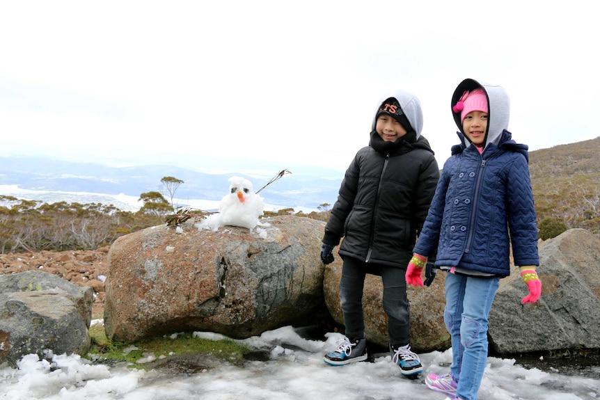 Young Malaysian tourists build snowman on Mt Wellington