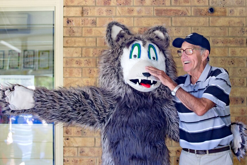 Man standing beside a large beast mascot, smiling 