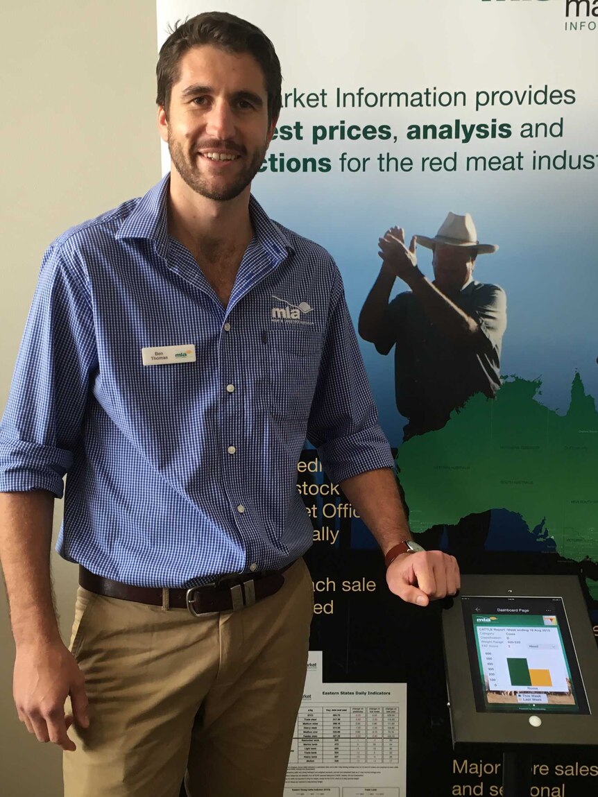Ben Thomas, market analyst for Meat Livestock Australia standing in front of a marketing poster