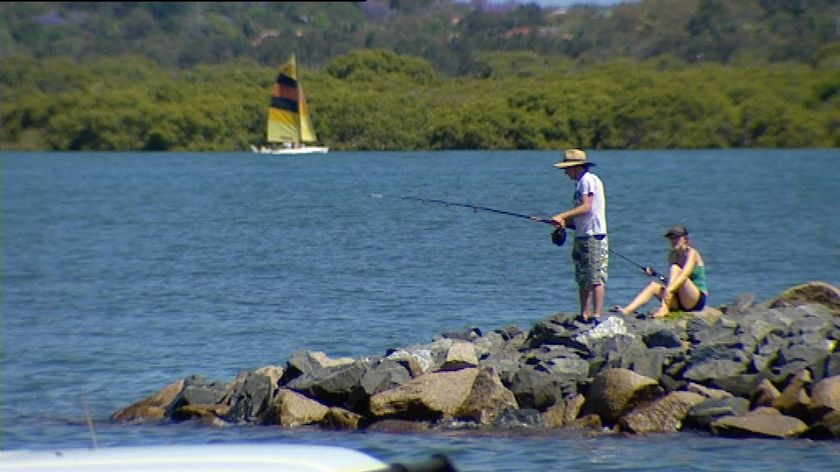 Generic TV still of two people fishing off rocks on Moreton Bay water in south-east Qld