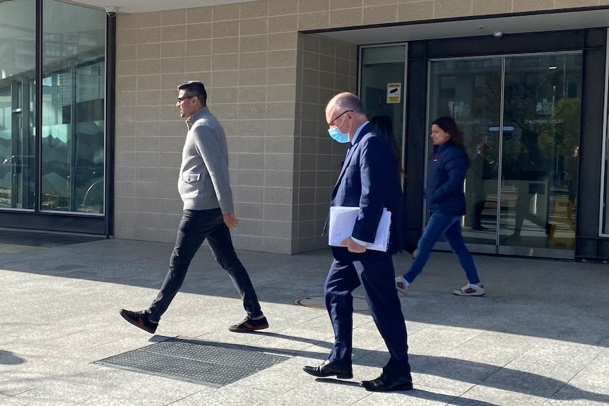 A man in a suit walks outside the ACT Magistrates court