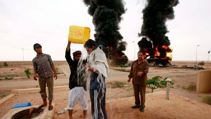 A man pours water on a friend before retrieving a dead person near the site of the explosion.