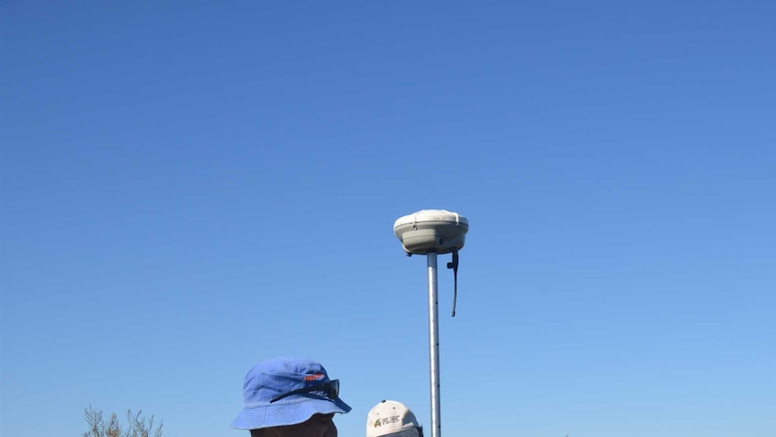 Two men standing in a paddock with aerial surveying equipment.