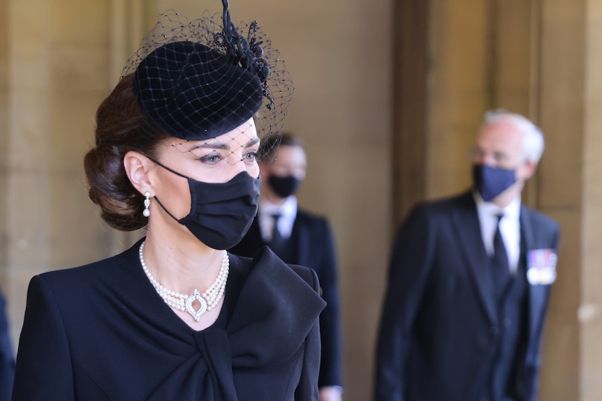 The Princess of Wales is pictured wearing black, a facemask and pearls with a diamond clasp.