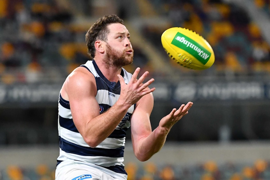 A Geelong AFL player has both arms prepared to take a mark against St Kilda in Brisbane.