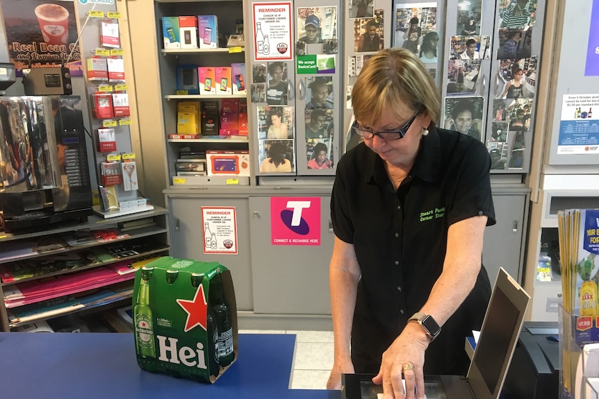 Fay Hartley scans an ID card inside of her Stuart Park liquor store.