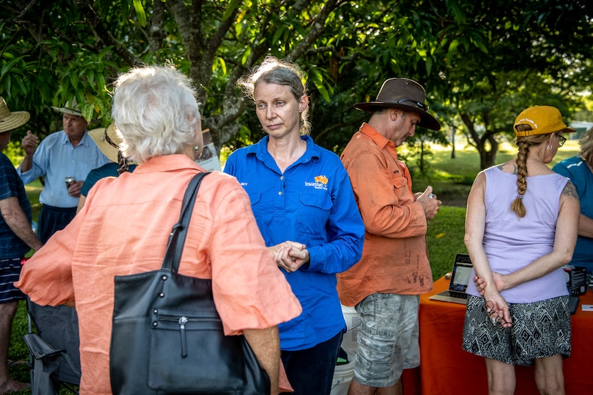A woman in a blue shirt talking to a group.