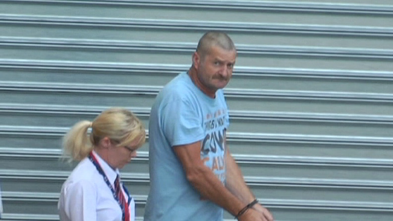 A man in handcuffs with a Sheriff's Officer.