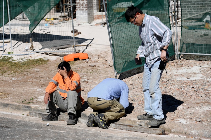 Workers from a nearby worksite gather following a man's death on a building site in Carlingford, northwest of Sydney.