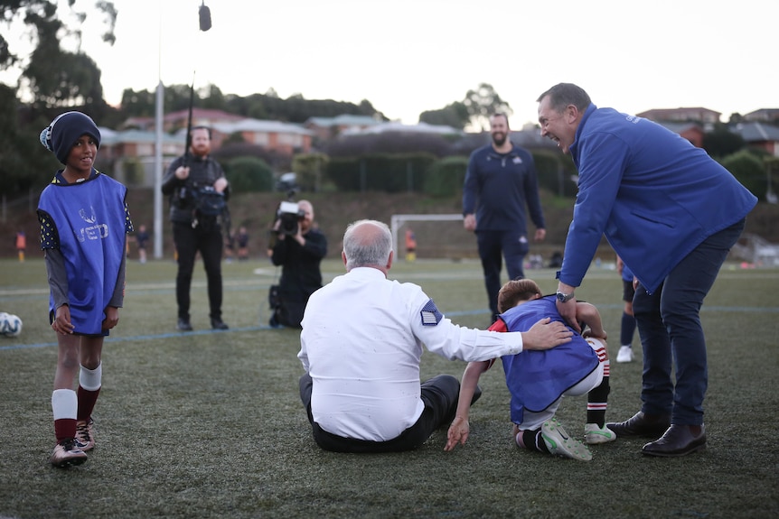 A man in a shit sits next to a child after he tackled him