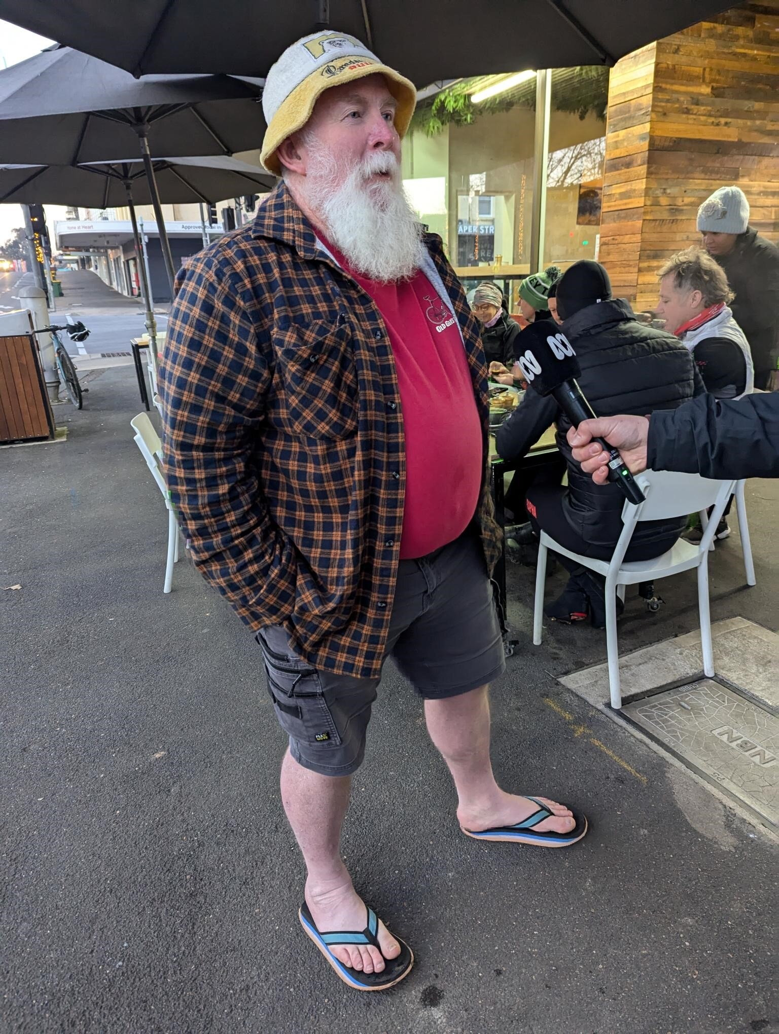 Man with a grey beard in shorts and a flannelette shirt