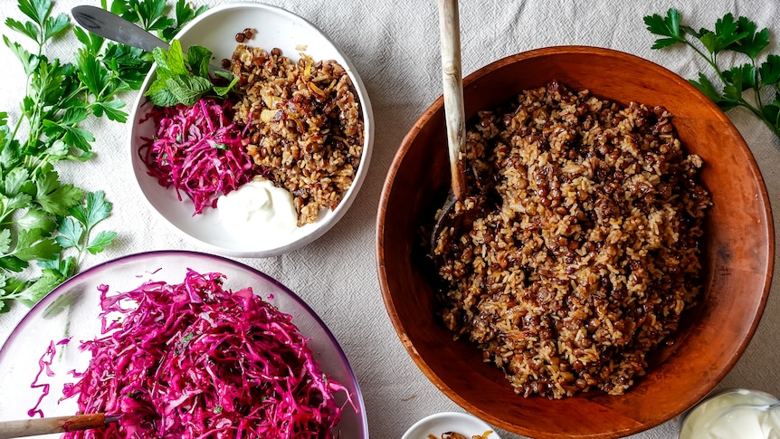 A large bowl of lentils and rice with caramelised onion alongside a bowl of sliced red cabbage and small bowl with both.
