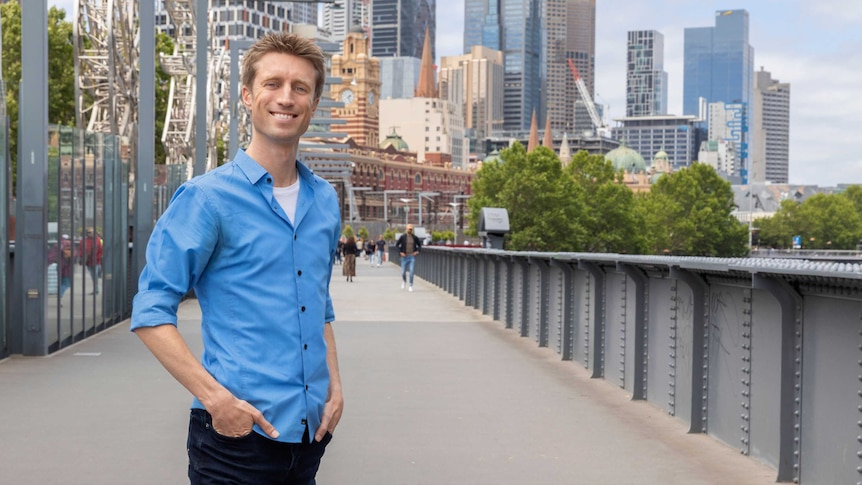 Sammy J standing on a bridge with Flinders Street station in the background.