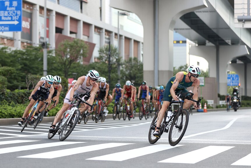 a man wearing a green lycra riding a bike in front of a group of men on bikes