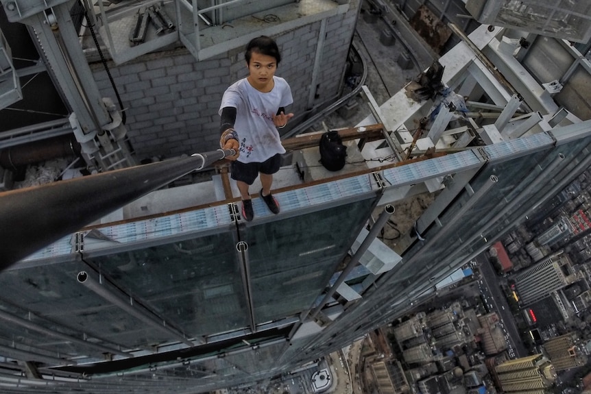 Wu Yongning takes a selfie while standing on a building ledge.