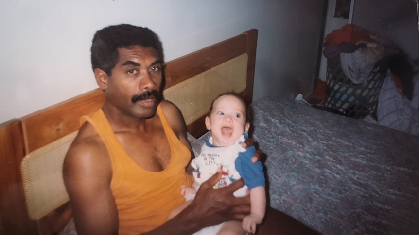 A film photo of a father holding his smiling baby