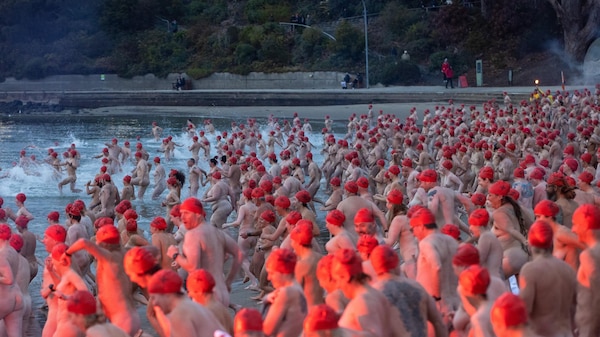 Side on view of a horde of swimmers rushing into water.