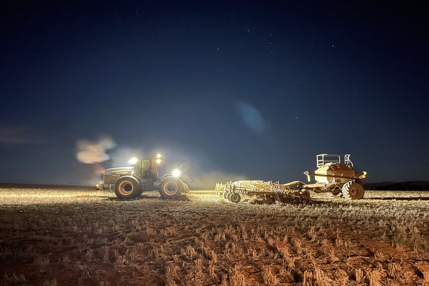 A header on a farm with grain at night time.