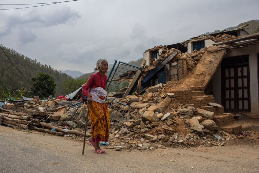 Elderly woman walks past Nepal rubble