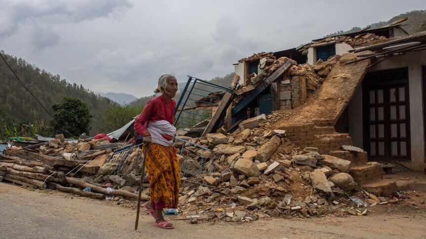 Elderly woman walks past Nepal rubble