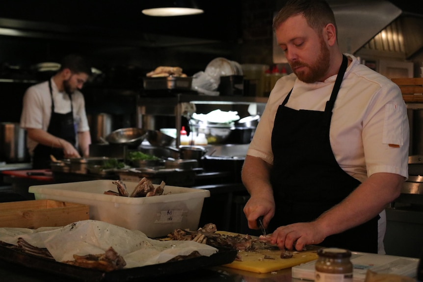 Chefs in kitchen chop food. 