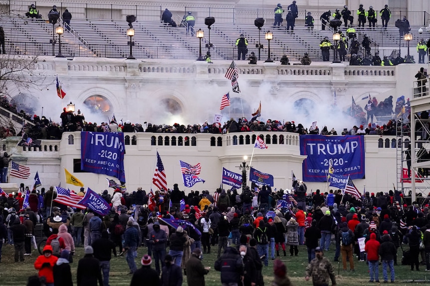Rioters gather before the Capitol with flags with smoke bombs. 