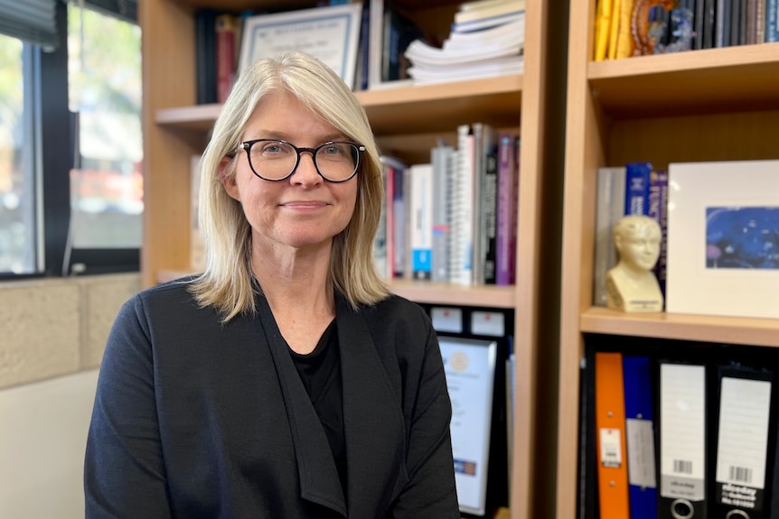 woman looking at camera in front of a bookshelf 