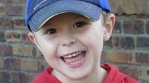 Smiling photo of four-year-old Tyrell Cobb wearing red jumper and a blue baseball cap.