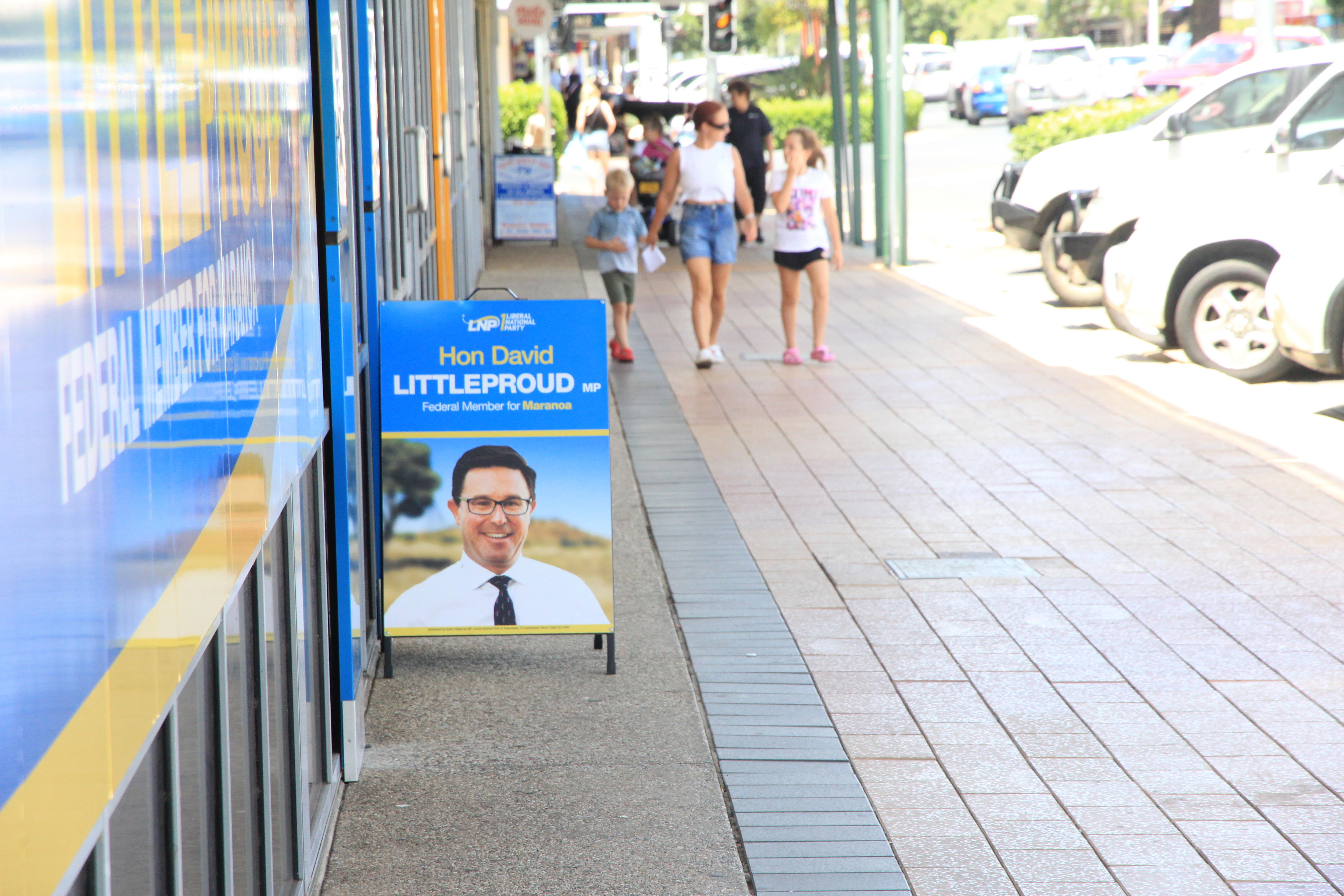 El cartel de un político en el sendero mientras pasa una familia.
