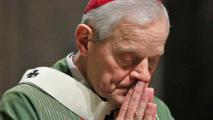 Cardinal Wuerl bowing his head and pressing his hands together in prayer.