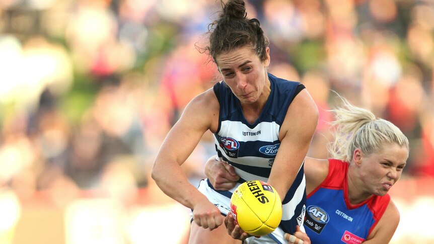 Rebecca Goring of the Cats is tackled by Katie Brennan of the Bulldogs.