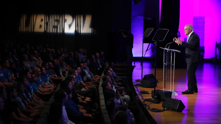 Scott Morrison speaks to a crowd in front of Liberal branding