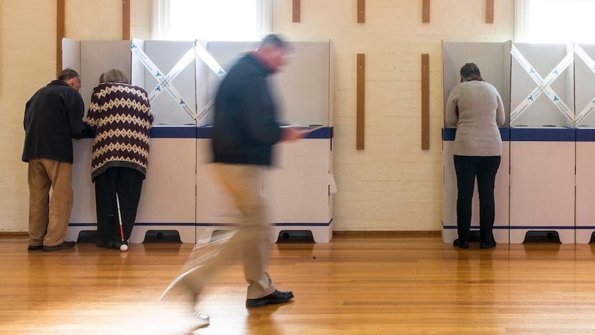 A man walks past polling booths as people vote