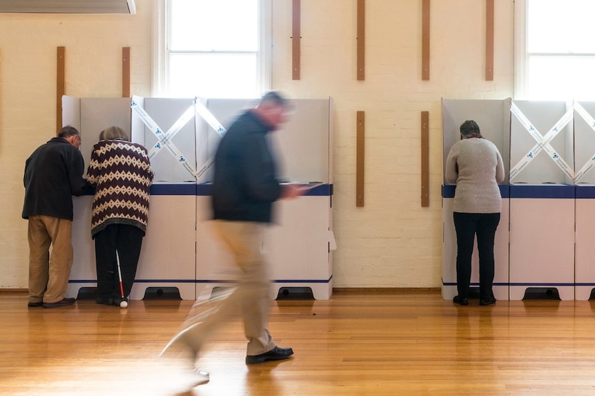 A man walks past polling booths as people vote