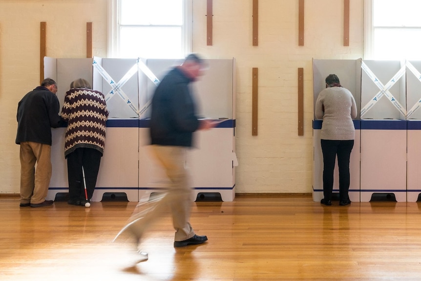 A man walks past polling booths as people vote
