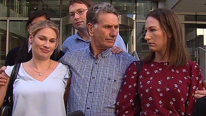 Gregory Johnston stands outside a Perth court flanked by his two daughters.