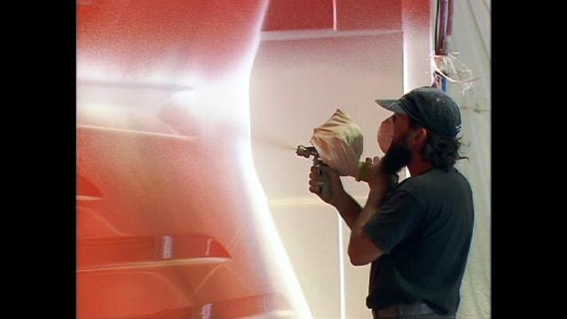 Man uses spray gun to paint ship hull